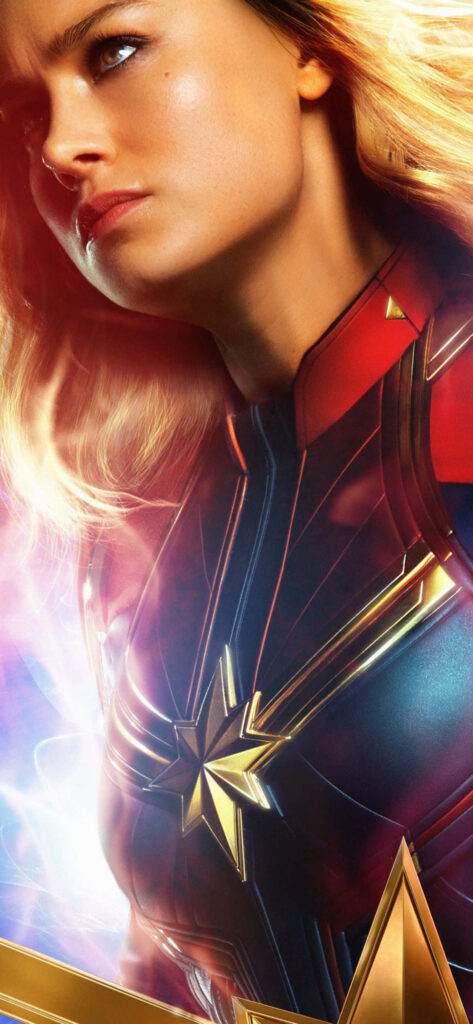 Brie Larson embodying the fierce Captain Marvel, ready to defend the universe in her vibrant superhero suit Wallpaper