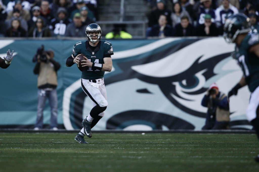 Carson Wentz in Philadelphia Eagles uniform preparing to pass on green football field action shot Wallpaper