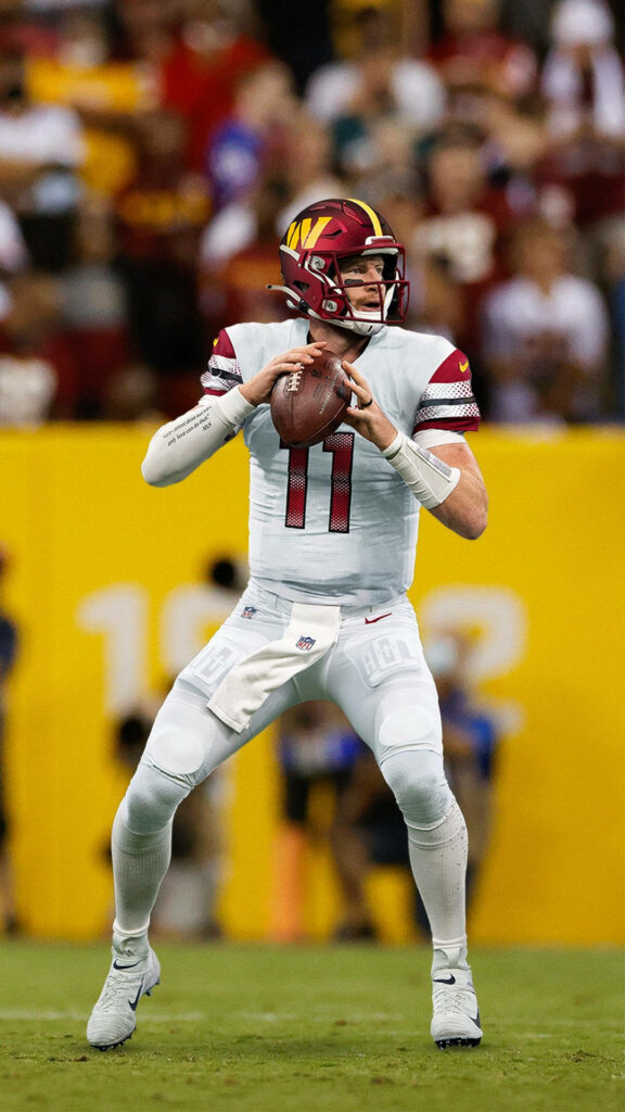Carson Wentz in Washington Commanders uniform ready to throw football during NFL game action Wallpaper