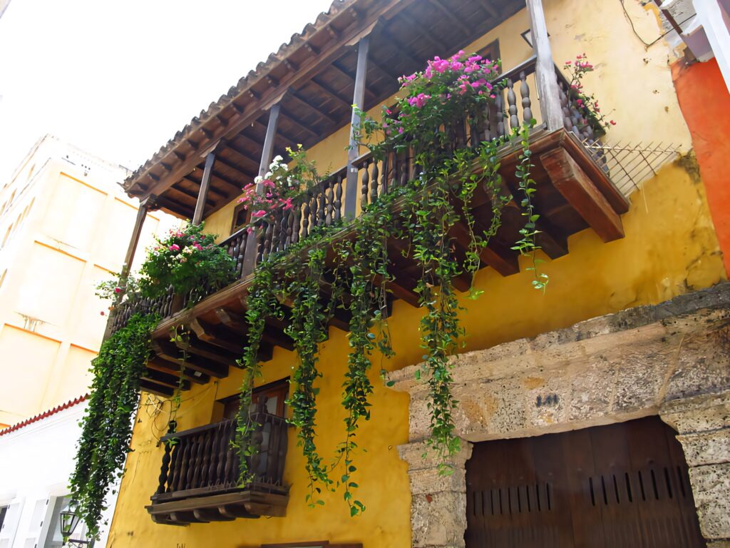 Cartagena yellow building with wooden balcony and green plants vibrant Colombian architecture wallpaper