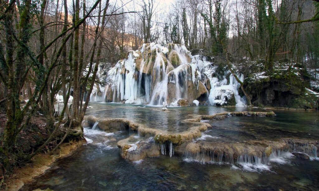 Cascade des Truffes waterfall in France with clear water flowing over mossy rocks winter scene Wallpaper