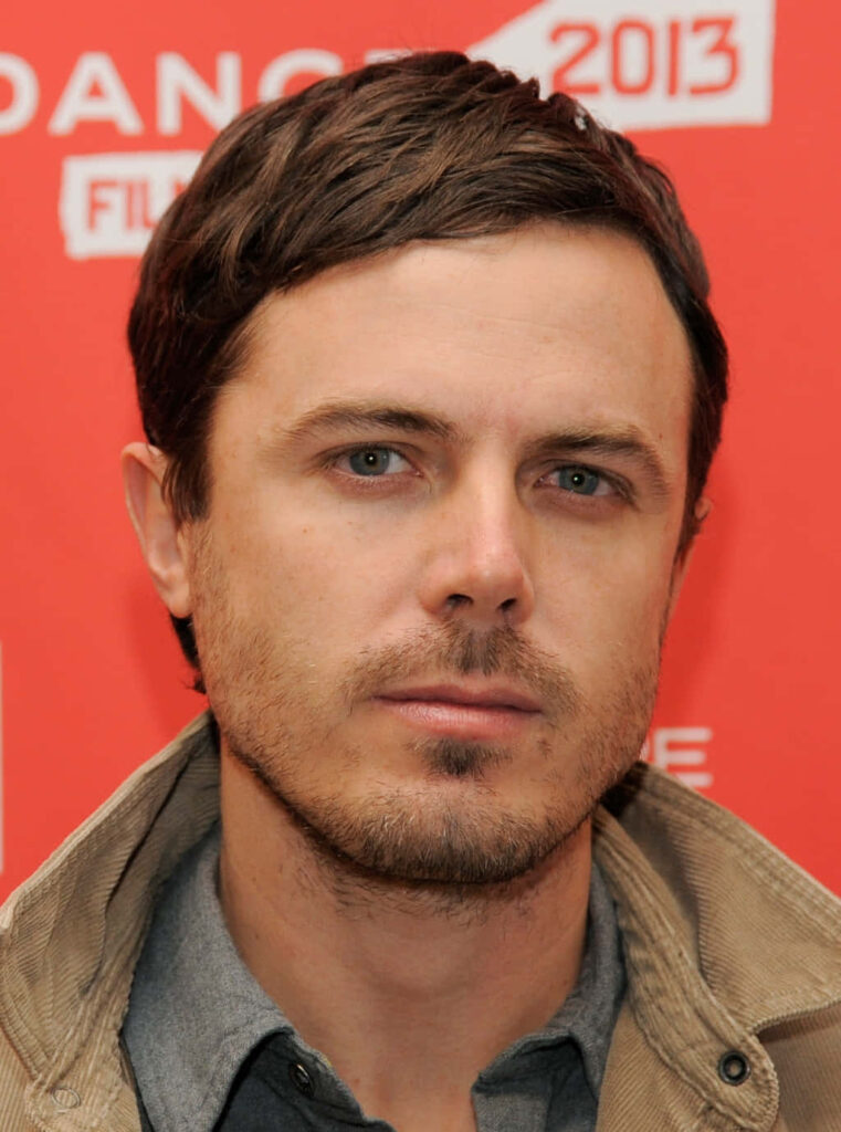 Casey Affleck close-up portrait on red background with white text highlighting casual style Wallpaper