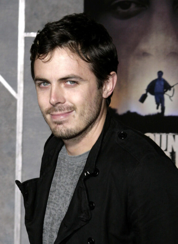 Casey Affleck candid portrait in dark jacket gray shirt cinematic muted background wallpaper