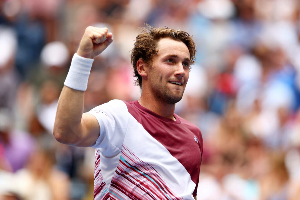 Casper Ruud smiling with fist pump at vibrant lively tennis event wallpaper background