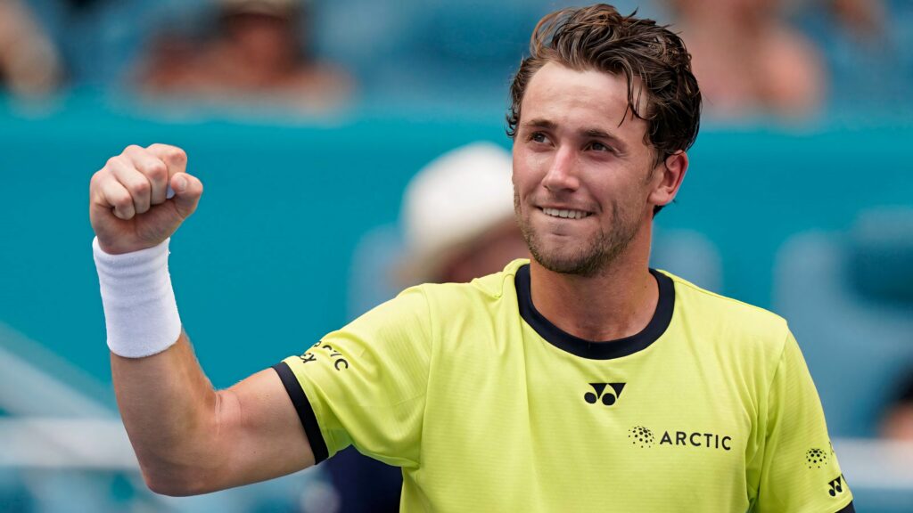 Casper Ruud celebrating on tennis court in neon green shirt with determined expression and energy Wallpaper