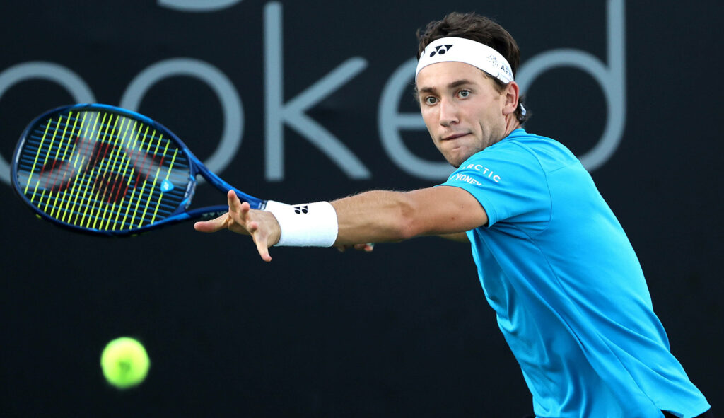 Casper Ruud hitting a focused forehand on tennis court wearing blue shirt and headband Wallpaper