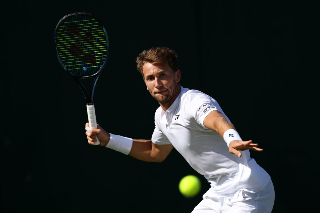 Casper Ruud in white tennis outfit focused hitting ball high-definition sports wallpaper background