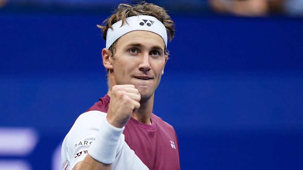Casper Ruud celebrates tennis victory with clenched fist on vibrant blue court showcasing determination Wallpaper