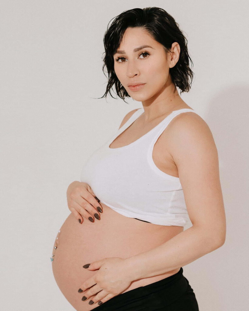 Cassie Steele pregnant in white tank top soft lighting neutral background calm expression Wallpaper