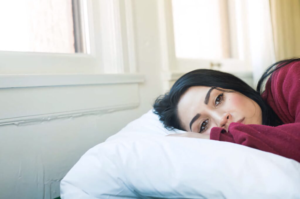 Cassie Steele resting in bed gazing out window in soft natural light serene contemplative mood Wallpaper