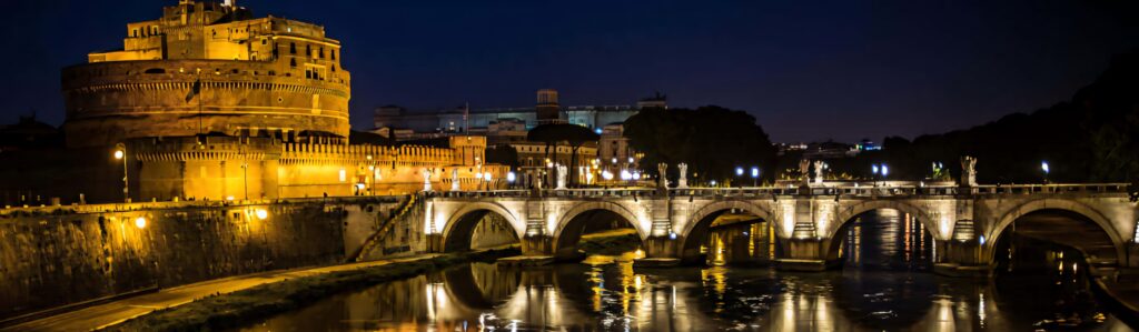 Castel Sant Angelo at night lit in gold with Ponte Sant Angelo bridge statues over river wallpaper