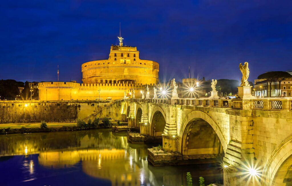 Night view of illuminated Castel Sant Angelo and stone bridge reflecting on calm Tiber River Wallpaper