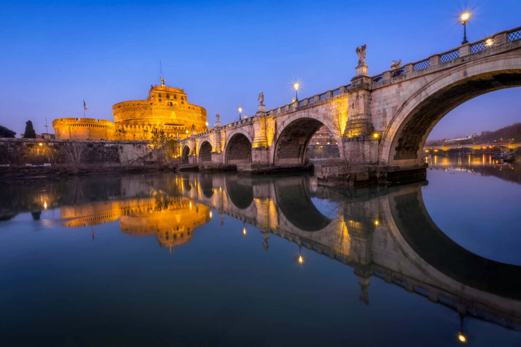 Castel Sant Angelo at dusk with golden lights reflecting on Tiber River in Rome wallpaper background