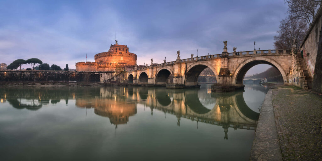Castel Sant Angelo and ancient Roman bridge illuminated at twilight with Tiber River reflections Wallpaper