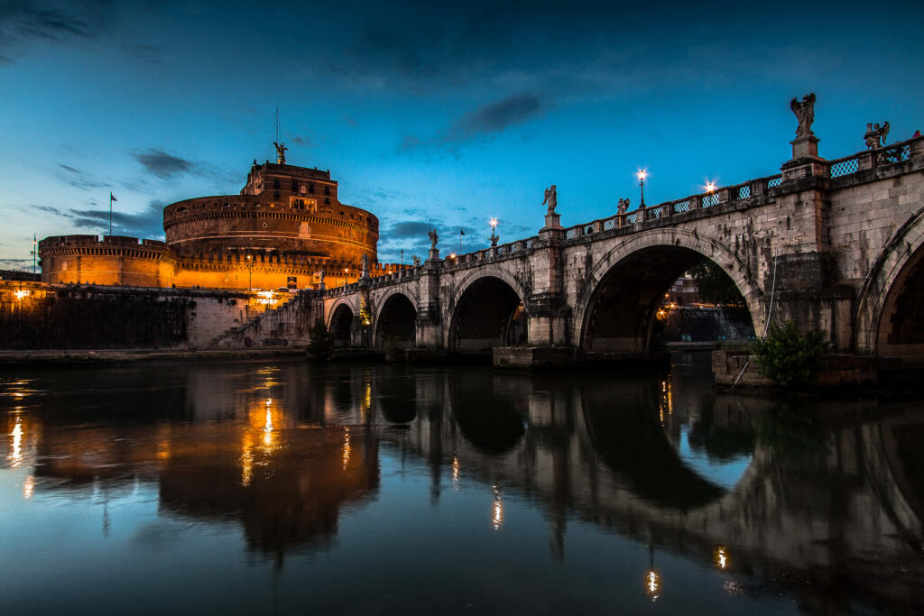Castel Sant Angelo and Hadrians Bridge lit at twilight reflected in calm Tiber River Rome wallpaper