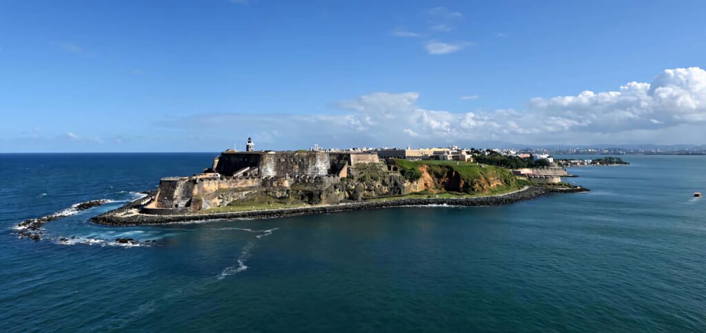Castillo San Felipe del Morro fortress on rocky shore with blue ocean and clear sky background Wallpaper