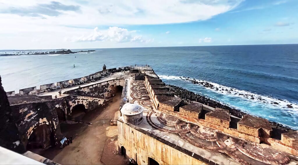 Historic Castillo San Felipe del Morro stone fort overlooking vibrant blue Atlantic Ocean coastline Wallpaper