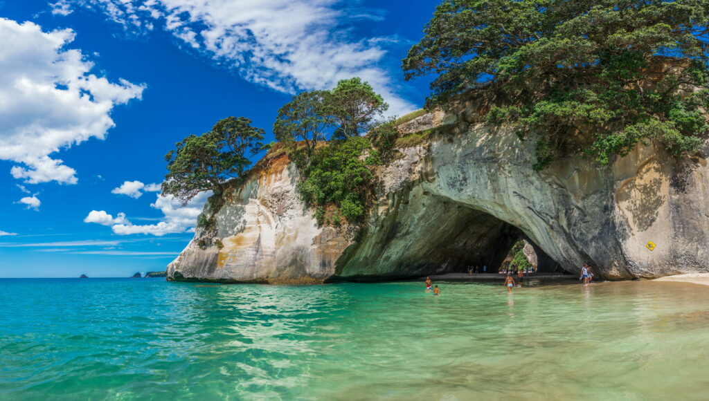 Cathedral Cove New Zealand limestone arch over turquoise waters and sandy beach under blue sky Wallpaper
