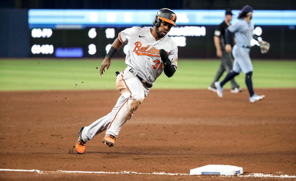 Cedric Mullins of Baltimore Orioles sprinting on brown baseball infield in dynamic game action Wallpaper