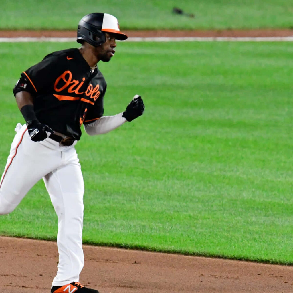 Cedric Mullins in Orioles uniform showing athleticism during key baseball game on green field background Wallpaper
