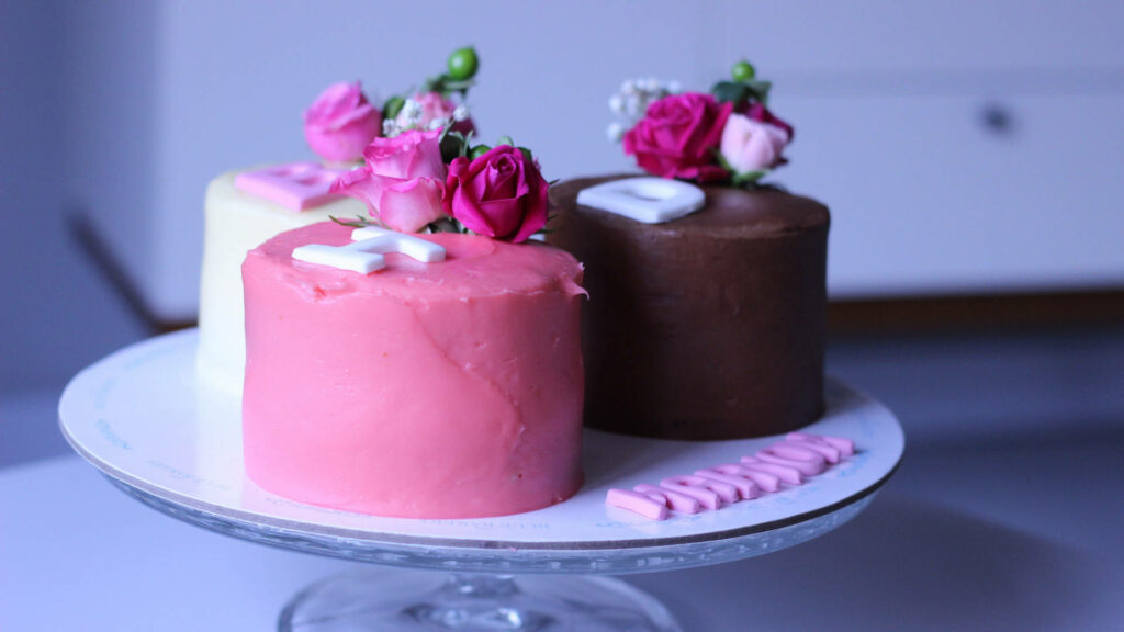 Floral Delights: Elegant Minimalist Cakes with Pink, White, and Chocolate Frosting on a Kitchen Counter - Celebrating Joyful Birthdays amidst Blooming Flowers Wallpaper