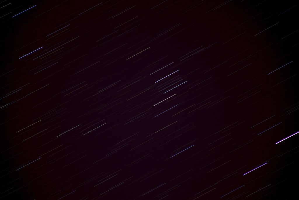 Celestial Streaks: Dynamic Dark Wallpaper of Stars in Motion