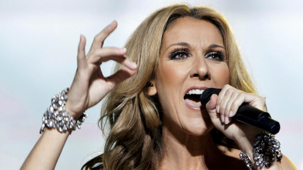 Celine Dion performing passionately on stage with vibrant lighting and detailed jewelry wallpaper