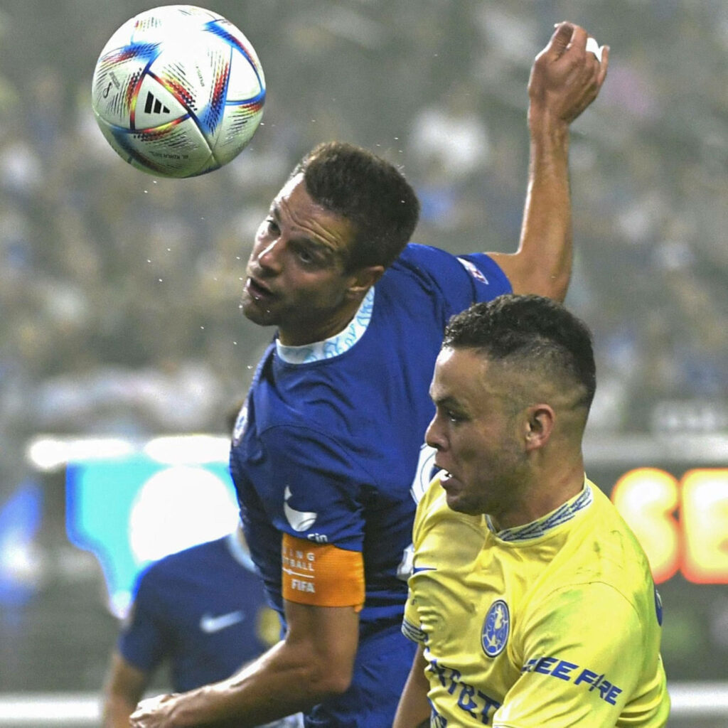 César Azpilicueta in blue kit challenges opponent for header during intense football match Wallpaper