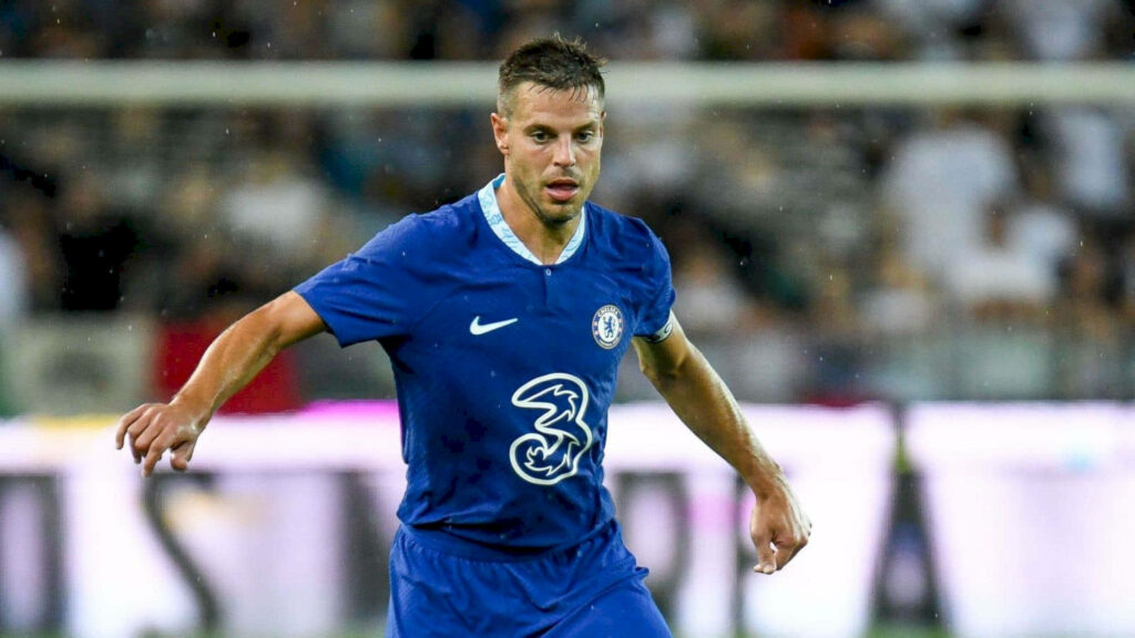 César Azpilicueta in Chelsea blue kit focused during intense match with blurred stadium fans Wallpaper