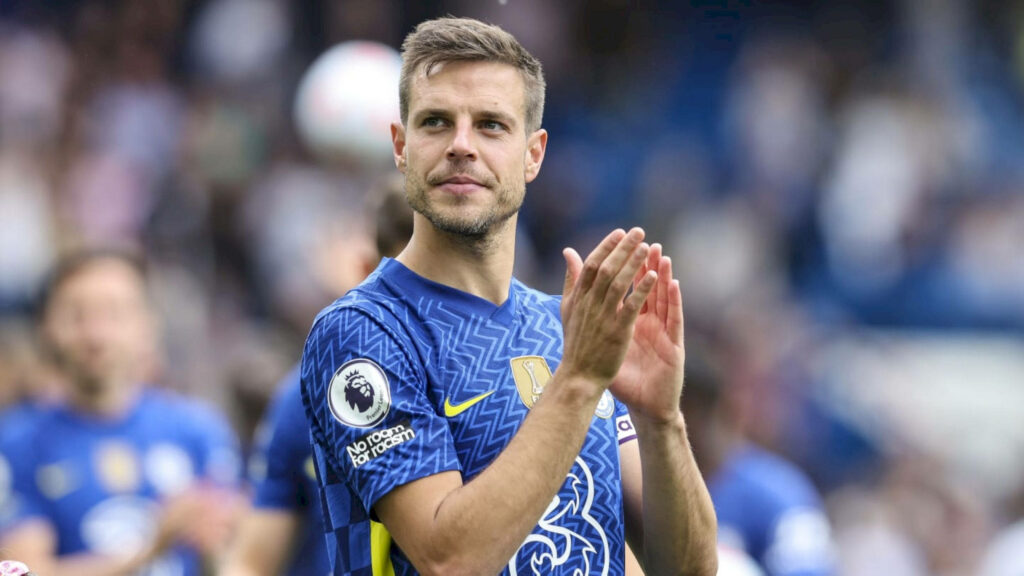 César Azpilicueta in Chelsea blue kit applauding on field with vibrant stadium lights background Wallpaper