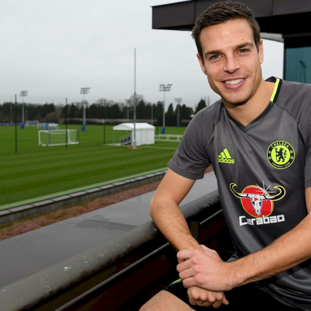 César Azpilicueta smiling in Chelsea training kit on vibrant green football pitch under cloudy sky Wallpaper