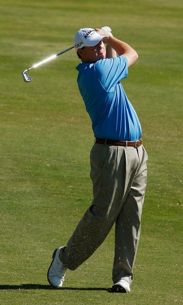 Chad Campbell mid-swing on lush green golf course with dynamic motion and bright outdoor lighting Wallpaper