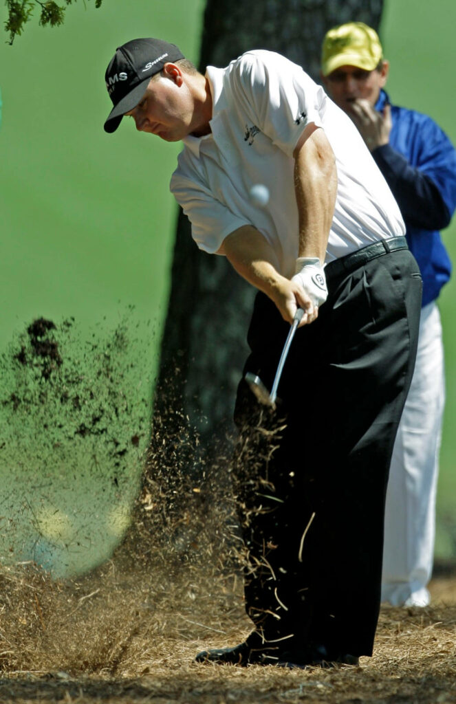 Chad Campbell mid golf swing hitting ball with flying grass and vibrant green course background Wallpaper