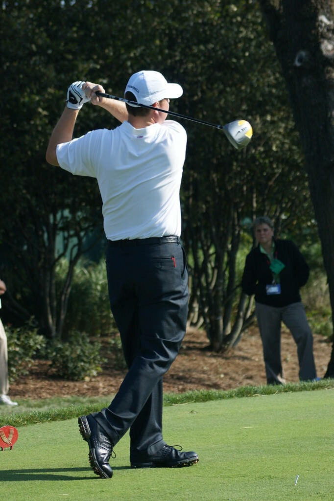 Chad Campbell mid-swing on lush golf course green with sunlight and professional golf attire Wallpaper