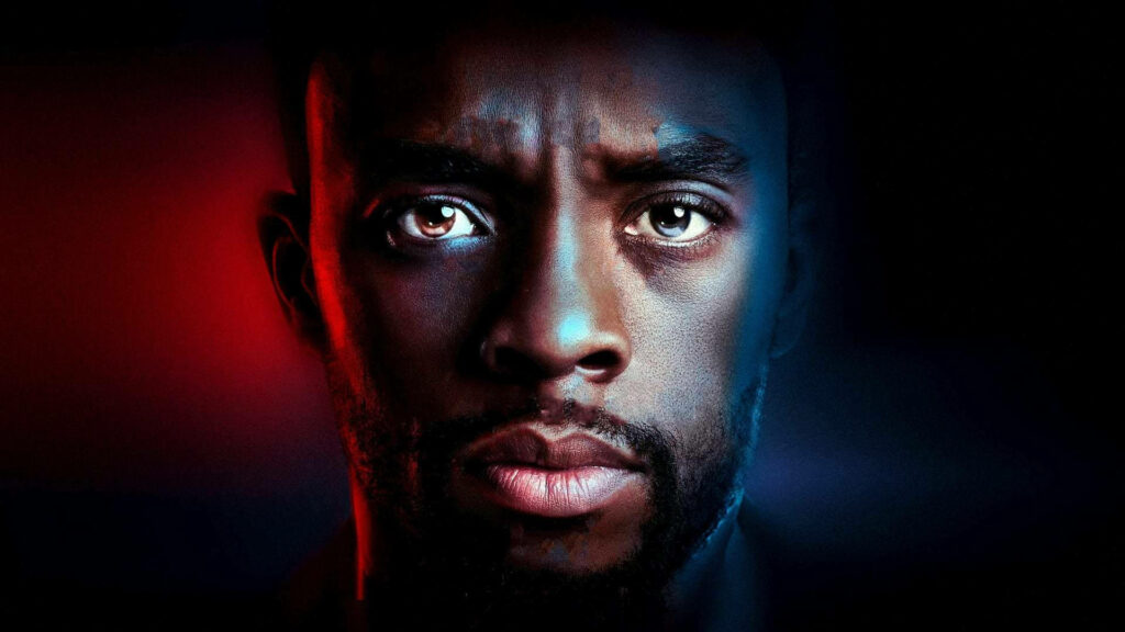 Close-up of Chadwick Boseman with intense gaze in cinematic red and blue lighting wallpaper background