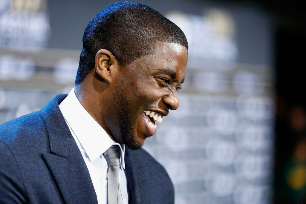 Candid side view of Chadwick Boseman laughing in sharp suit vibrant natural photographic wallpaper