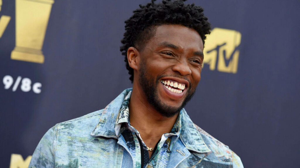 Chadwick Boseman smiling in light denim jacket at music TV event purple backdrop vibrant wallpaper