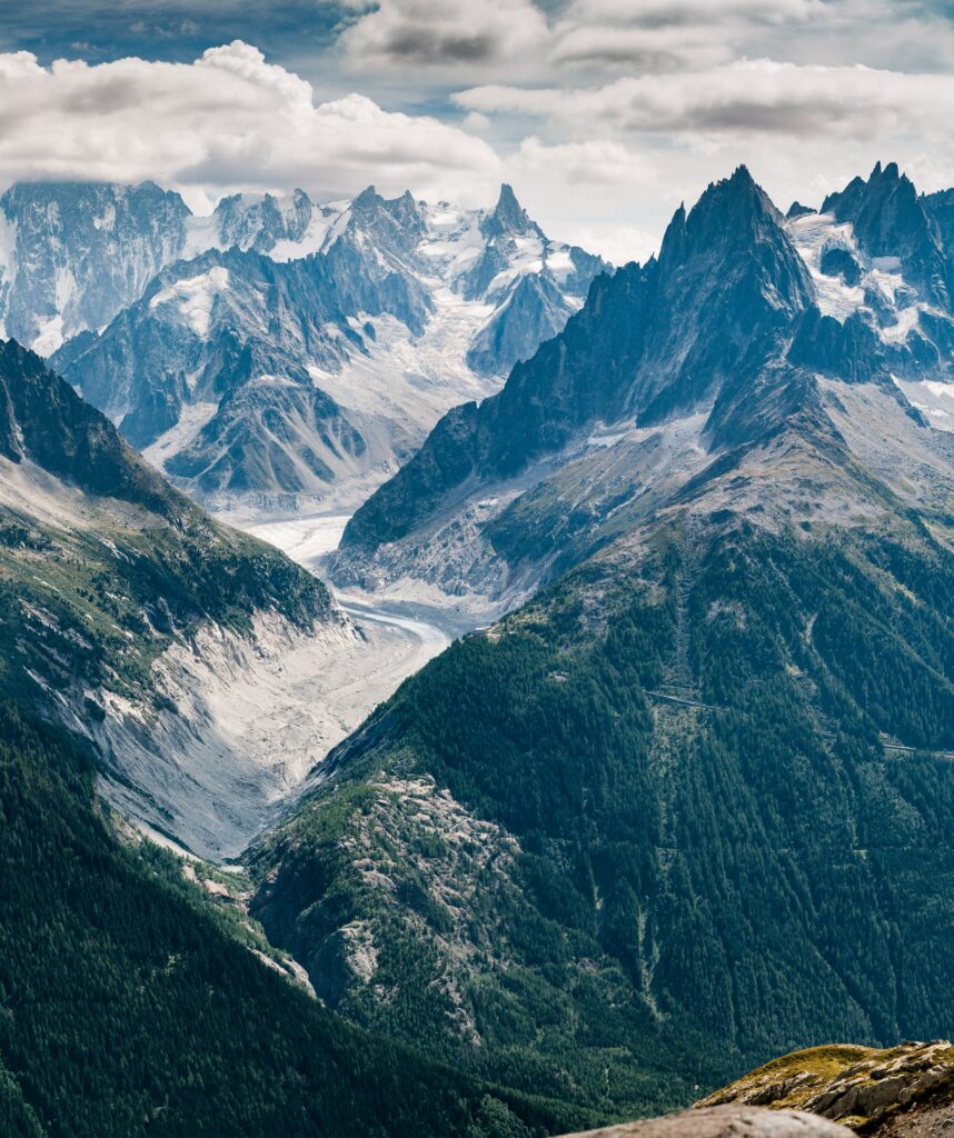 Aerial view of snow-capped Chamonix peaks lush green valleys and winding alpine road scenery wallpaper