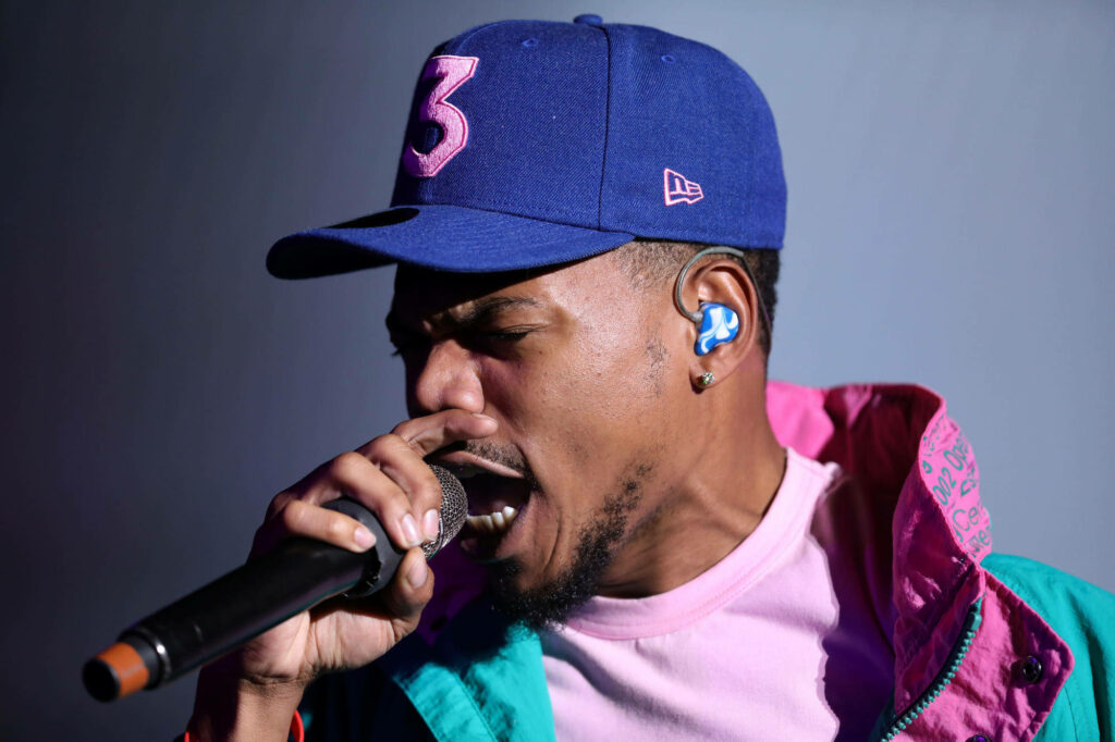 Chance The Rapper performing live in pastel jacket and blue cap with pink 3 vibrant stage lighting Wallpaper