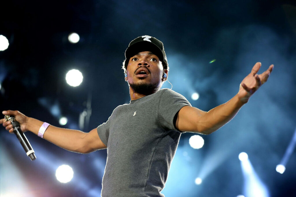Chance The Rapper on stage with open arms under blue lights in a dynamic live performance Wallpaper