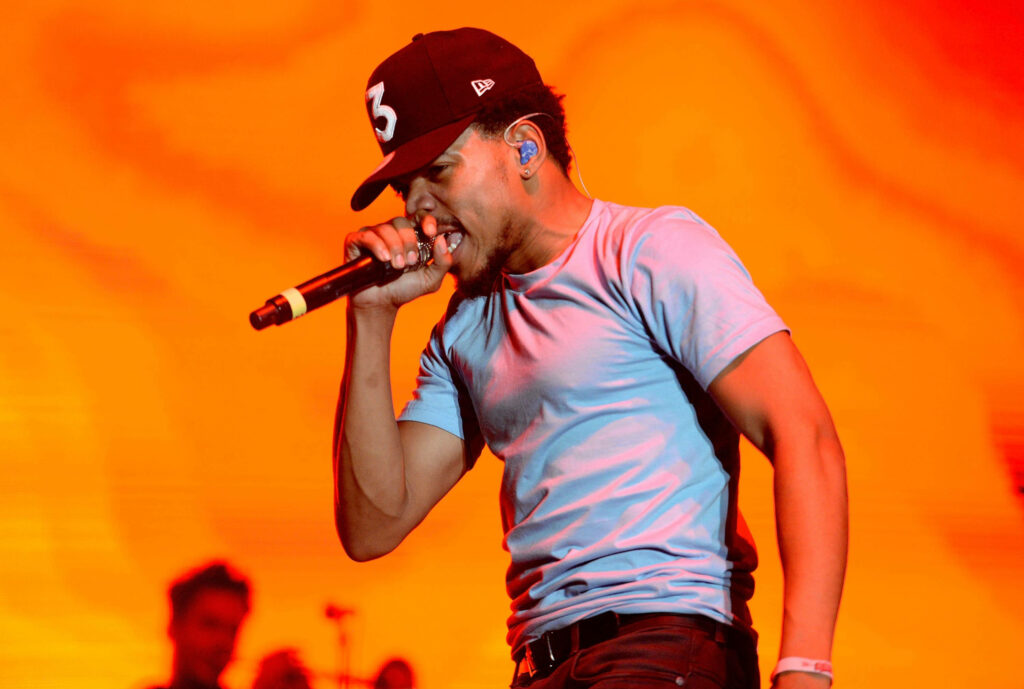 Chance The Rapper performing energetically with vivid orange background vibrant music wallpaper