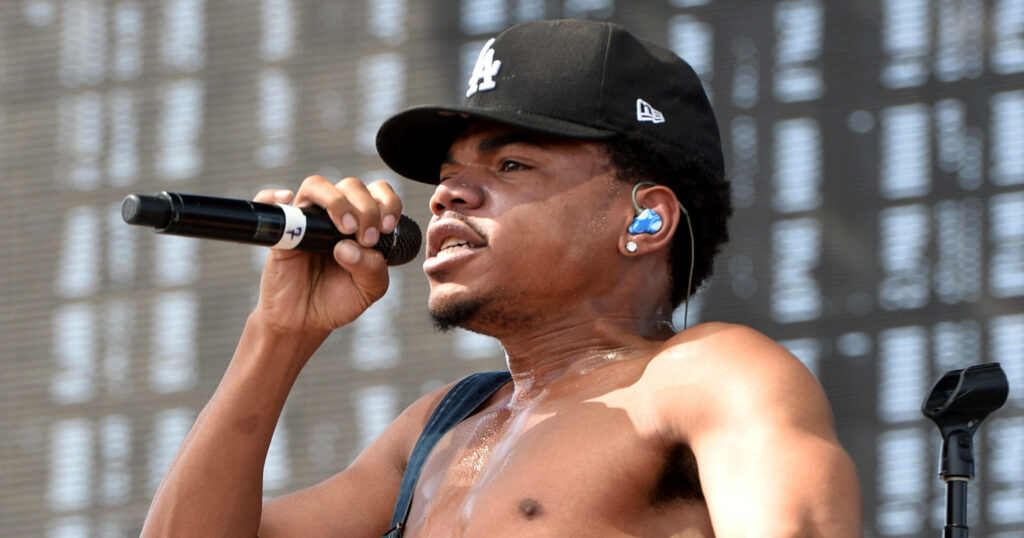 Chance The Rapper shirtless performing live wearing black LA cap and blue earpiece on stage Wallpaper