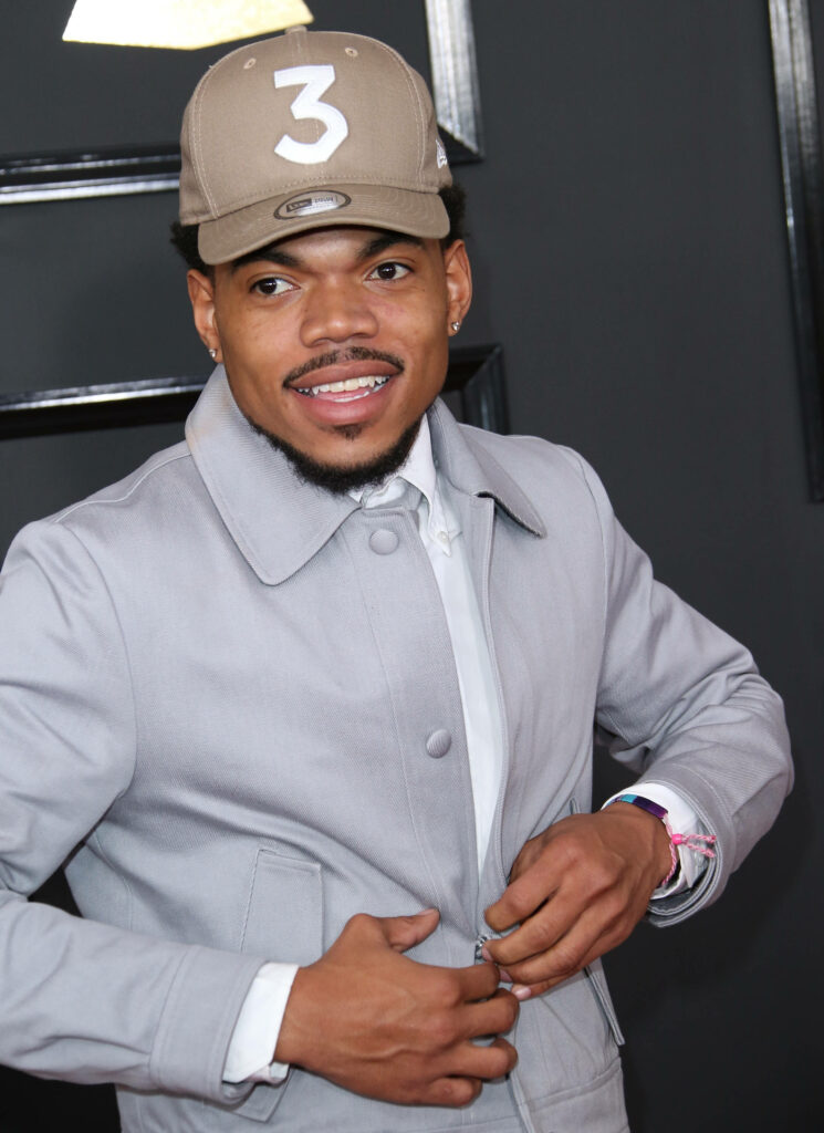 Chance The Rapper in grey suit and tan number 3 cap exuding confident urban style on dark background Wallpaper