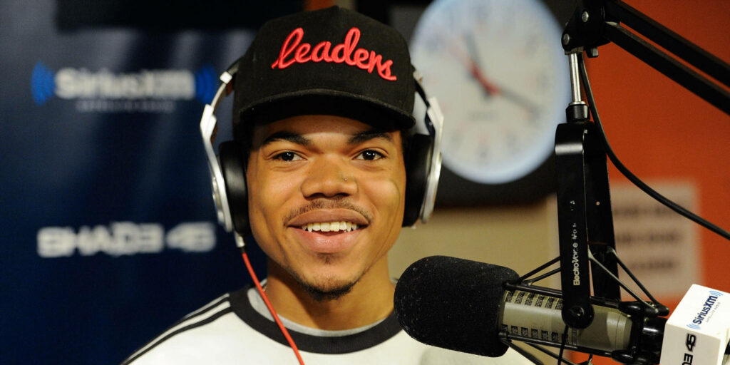Chance the Rapper in radio studio wearing black leaders cap headphones SiriusXM microphone clock background Wallpaper