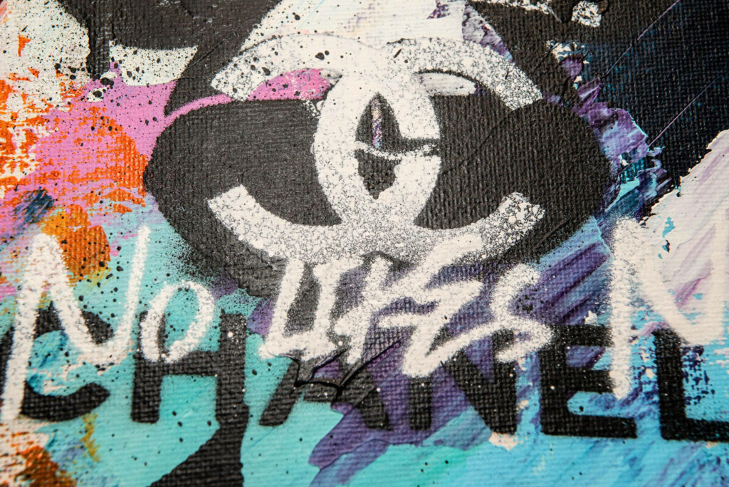 Chanel logo white bold on colorful paint splatter graffiti background luxury street art wallpaper