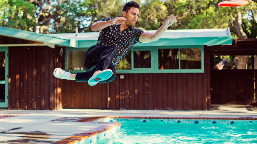 Channing Tatum mid-air jump over pool outdoor modern wooden house lush greenery background Wallpaper