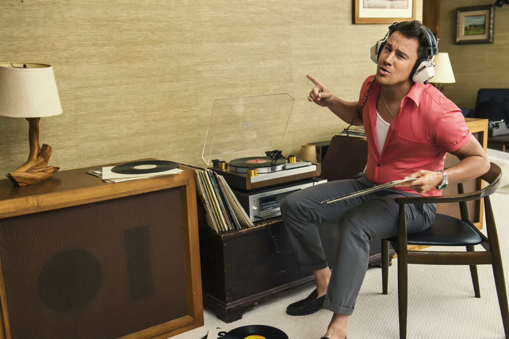 Channing Tatum listening to vinyl records with headphones in a stylish retro-themed room Wallpaper
