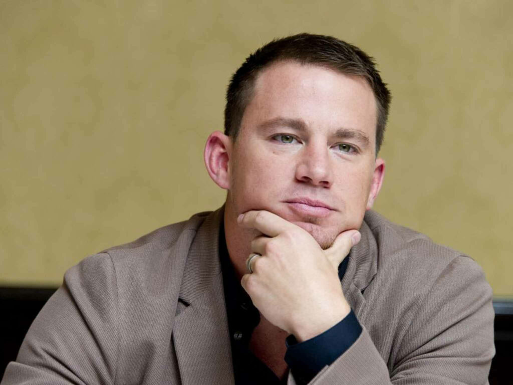 Channing Tatum thoughtful portrait resting chin on hand against simple wallpaper background