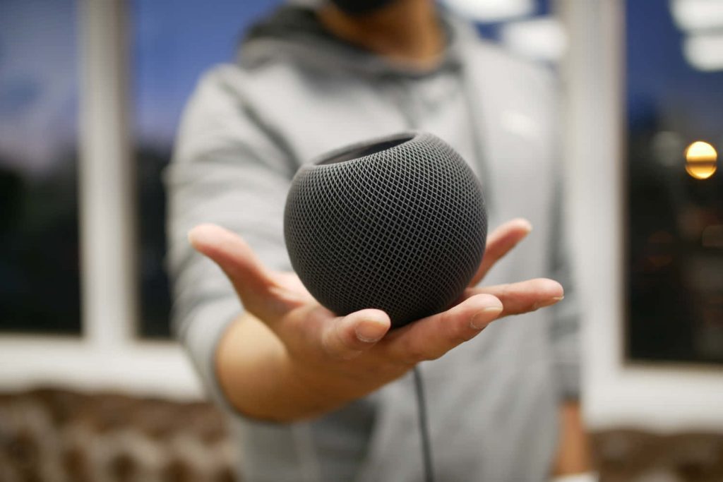 Close-up of charcoal Apple HomePod mini showing mesh texture with blurred soft background Wallpaper