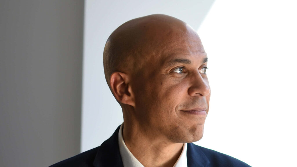 Cory Booker smiling confidently in soft natural light showcasing positive leadership energy wallpaper